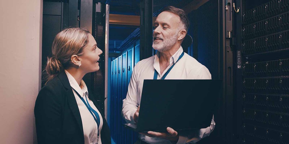 Two IT specialists talking in a server room